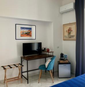 a bedroom with a tv and a chair and a desk at Villa Striano Boutique in Capri