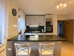 a kitchen with white cabinets and a counter with two chairs at 4 Zimmer Wohnung, 6 Bed, Küche, Waschmaschine, Wlan, Garden, free Parking in Tacherting