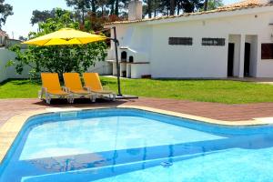 ein Paar Stühle und ein Sonnenschirm neben einem Swimmingpool in der Unterkunft Villa near Beach & Lisbon in Corroios