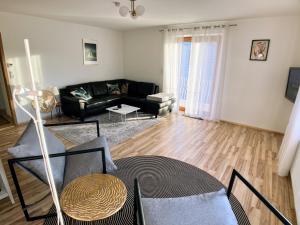 a living room with a black couch and a table at 4 Zimmer Wohnung, 6 Bed, Küche, Waschmaschine, Wlan, Garden, free Parking in Tacherting