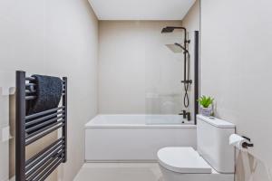 a white bathroom with a toilet and a bath tub at Stylish new-build, FREE parking, 10 minutes to NEC & BHX airport in Birmingham +26 photos