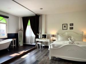 チェンマイにあるNidhra Lanna Hotel Chiang Maiのベッドルーム1室(ベッド1台、デスク、バスタブ付)