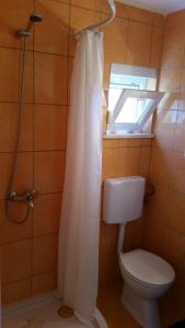 a bathroom with a toilet and a shower curtain at Holiday Home White House in Sumartin