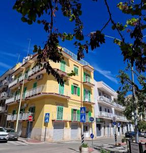 a yellow building with green doors and windows on a street at Domus Nicolaus in Giovinazzo