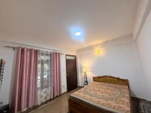 a bedroom with a bed and a window with a curtain at Sherpa Retreat in Sonāda +4 photos