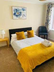 フォート・ウィリアムにあるWallace Houseのベッドルーム1室(黄色い毛布と椅子付きのベッド1台付)