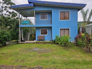a blue house with a balcony and a yard at Full equipado, WiFi, AC, vista volcán, 1er piso in Fortuna