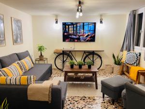a living room with a couch and a bike on the wall at Airport Cottage House in Artemida