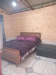 een slaapkamer met een bed in een houten kamer bij Cabaña Anita in Cerrillos