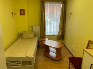 a small bedroom with a bed and a table at Apartment Hotel Rubini in Ventspils