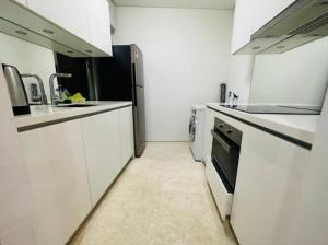 a kitchen with white cabinets and a black refrigerator at Vortex Premium Apartment klcc in Kuala Lumpur