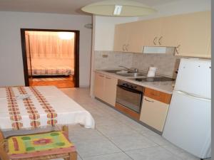 a kitchen with a refrigerator and a table and a sink at Apartments Sun Gardens in Privlaka