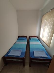 two beds in a small room with a window at Apartman Relax in Bijela