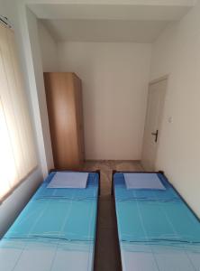 two beds in a small room with two windows at Apartman Relax in Bijela