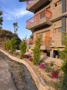 a building with a balcony and flowers in front of it at Shalom Hillcrest Inn in Shimla