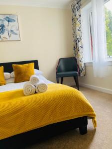 フォート・ウィリアムにあるWallace Houseのベッドルーム1室(黄色い毛布と椅子付きのベッド1台付)
