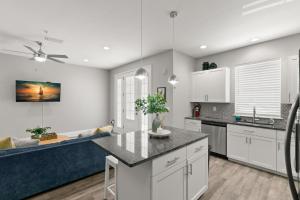 cocina con armarios blancos y sofá azul en Canopy Couplet - 2 Upscale Condos by Main St, en Safety Harbor