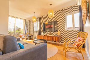 a living room with a couch and a tv at AfroBoHome, Expérience Atypique, clim, 2 à 6 personnes, Proche centre Nîmes, Garage clos in Nîmes