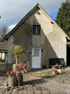 a small house with a white door and a bench at The Garden House in Dewlish