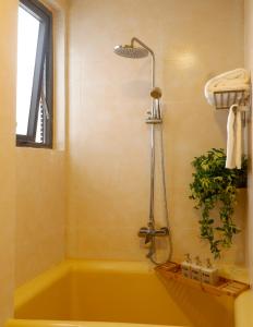 a yellow bath tub with a shower in a bathroom at Tasme Hotel in Da Lat