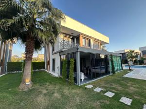 a house with a palm tree in the yard at Villa Yılmaz dream holiday in Kuşadası