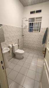 a white bathroom with a toilet and a sink at Zeimet Villa - Bujumbura in Mutobo