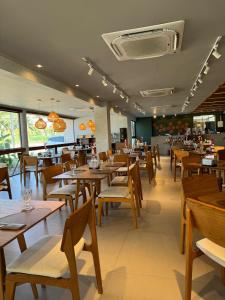 a dining room with wooden tables and chairs at Flat em Muro Alto - Porto de Galinhas - Malia Beach in Ipojuca