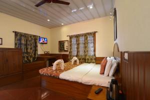 um quarto com uma cama e uma televisão em Tusker Towers em Thekkady