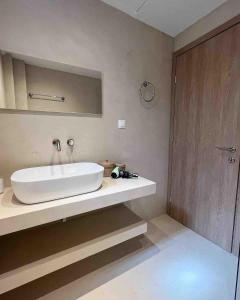 ein Badezimmer mit einem weißen Waschbecken und einem Spiegel in der Unterkunft Casa di Palma Beach Front in Pefkohori
