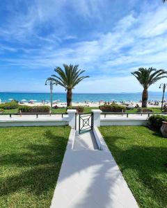 ein Gehweg mit Palmen und dem Strand im Hintergrund in der Unterkunft Casa di Palma Beach Front in Pefkohori