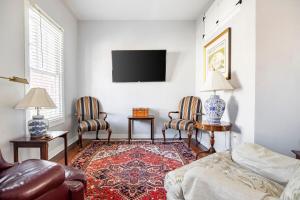 ein Wohnzimmer mit zwei Stühlen und einem Fernseher in der Unterkunft HISTORIC DOWNTOWN KING BED COTTAGE- PARKING and PATIO in Savannah