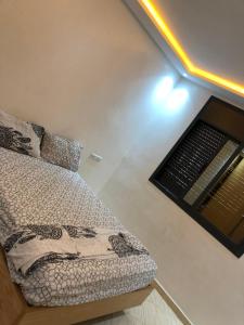 ein kleines Schlafzimmer mit einem Bett und einem Fenster in der Unterkunft Appartement cosy 1er étage in Kenitra