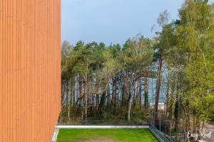 un edificio arancione con un campo di erba e alberi di PINEA apartament studio a Pobierowo