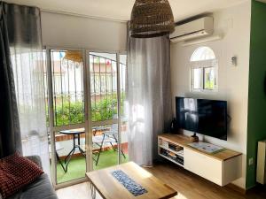 a living room with a television and a balcony at Casa Verde - Ground floor apartment next to the beach in Torrox Costa