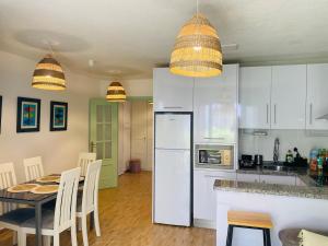 a kitchen with a table and a white refrigerator at Casa Verde - Ground floor apartment next to the beach in Torrox Costa