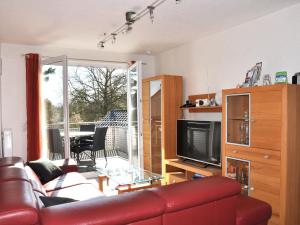 a living room with a red leather couch and a television at Ferienwohnungen im Veenhuus - Tierfreundlich in Kellenhusen