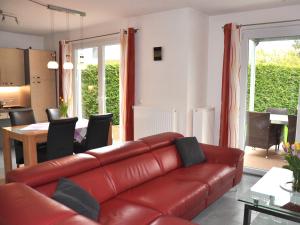 a living room with a red leather couch and a table at Ferienwohnungen im Veenhuus - Tierfreundlich in Kellenhusen