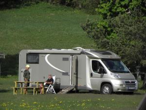 a man is sitting in front of a camper at Nationalpark-Camping Großglockner in Heiligenblut