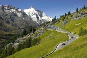 a winding road in the mountains with a snow covered mountain at Nationalpark-Camping Großglockner in Heiligenblut