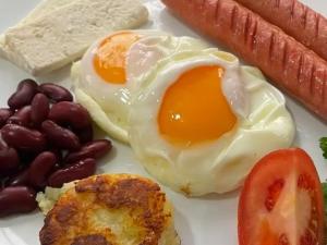 a plate with an egg and a sausage and a tomato at Ali guest house in Sary-Mogul