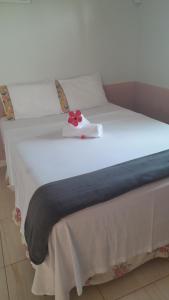 a white bed with a red flower on top of it at Pousada Terra de Minas in Aristeu