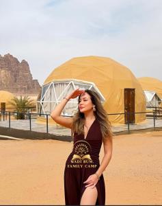 une femme debout devant une tente dans le désert dans l'établissement RUM FAMiLY BUBBLES &BEDOUIN CAMP, à Wadi Rum
