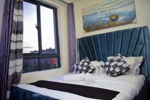 una camera da letto con un letto con testiera blu e una finestra di Brenda luxury homes a Nairobi