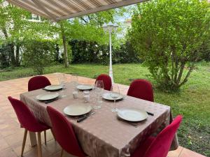 un tavolo di legno con sedie rosse intorno con bicchieri e piatti di Villa Nature à TOULOUSE a Tolosa