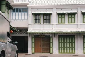 un edificio bianco con finestre verdi e una porta di SuXiang - Chinatown, Bangkok a Bangkok