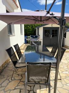 een tafel en stoelen onder een parasol op een terras bij The House in Medulin