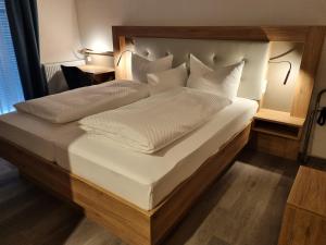a large bed with white sheets and pillows at Hotel Julia am Deich in Norddeich