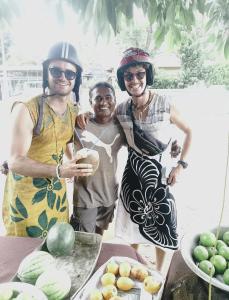 trois personnes portant des casques debout à côté d'une table avec des fruits dans l'établissement Farm House Hostel, à Negombo