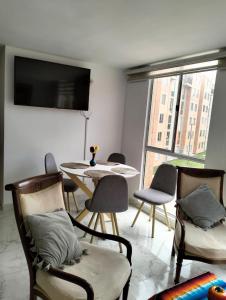 a living room with chairs and a table and a flat screen tv at Apartamento Le petit prince in Paipa