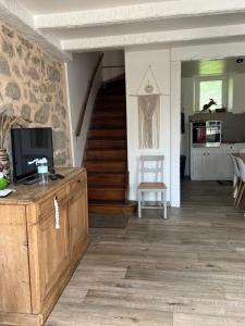 a living room with a tv and a staircase at Chez mémé in Ussel